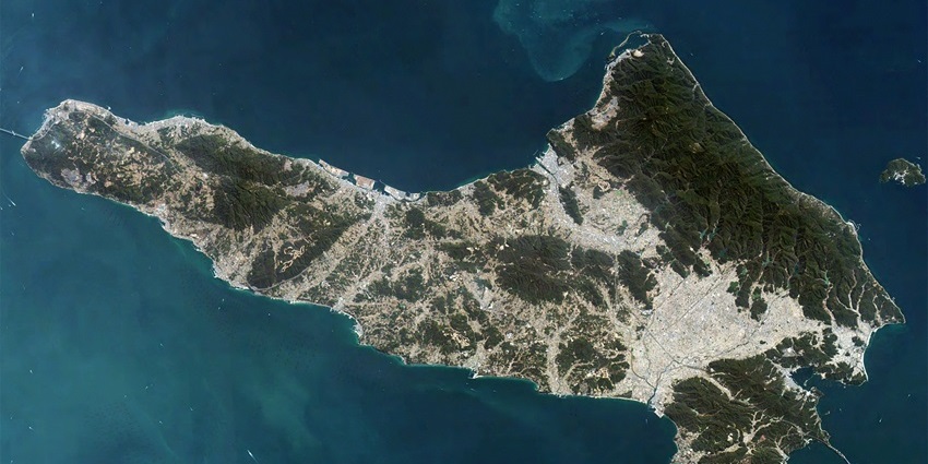 Awaji Island coastline with calm sea, sandy beach, and green hills in the background.