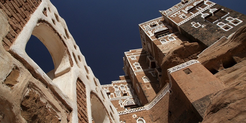 Traditional multi-story stone palace was built atop a large rock formation with clear skies.