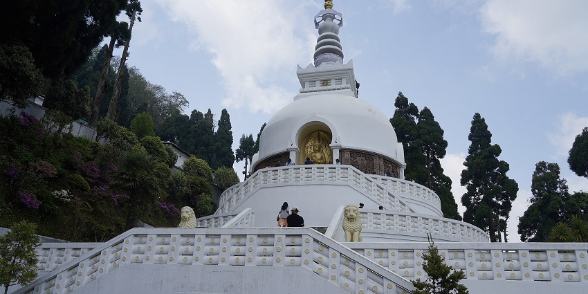 Darjeeling Peace Pagoda with the white architectural building, lion statues and people visiting.