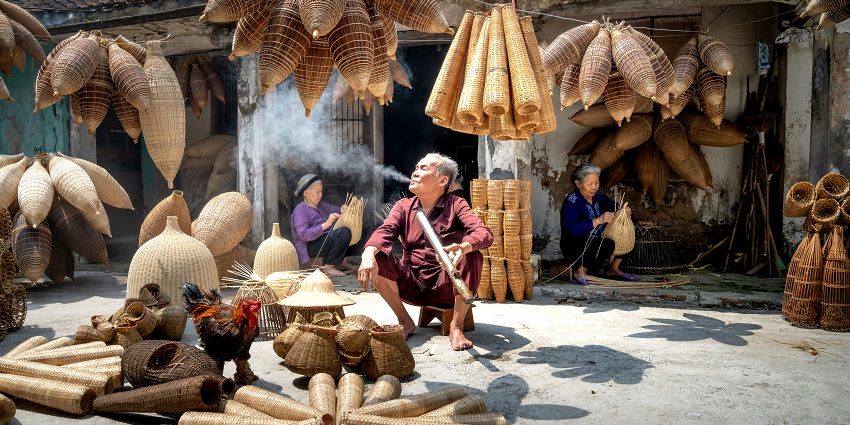 Woman sitting on a pile of bamboo sticks, surrounded by scattered wood and debris