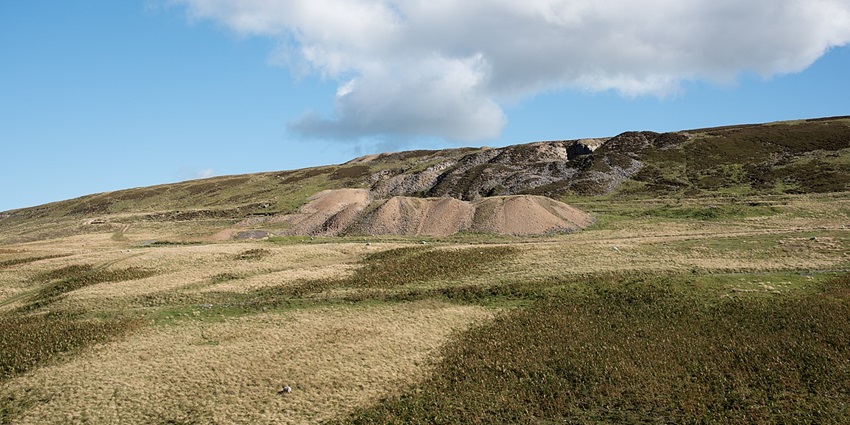Denniston mine site with green grass plains, under the cloudy blue sky in New Zealand
