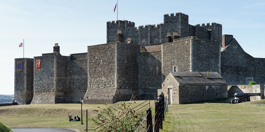Dover Castle with traditional architecture, multiple flags on the top and people sitting