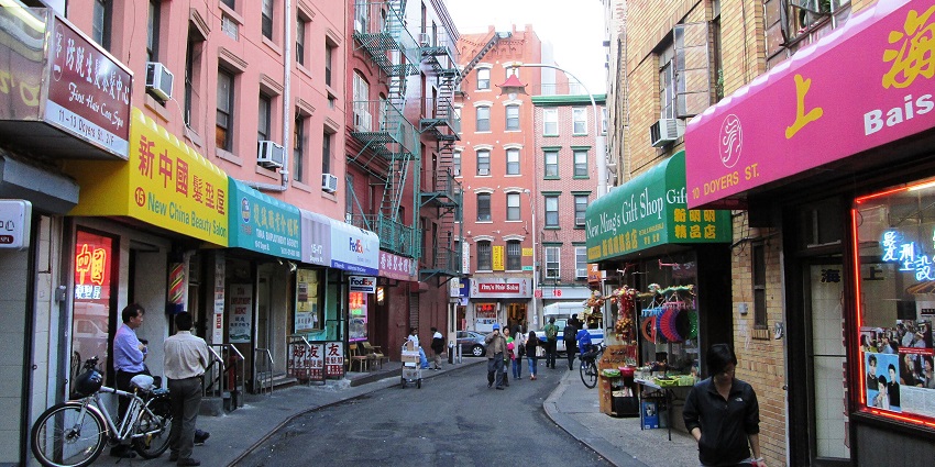 Doyers Street in Chinatown with people walking on the side, bicycles parked and shops