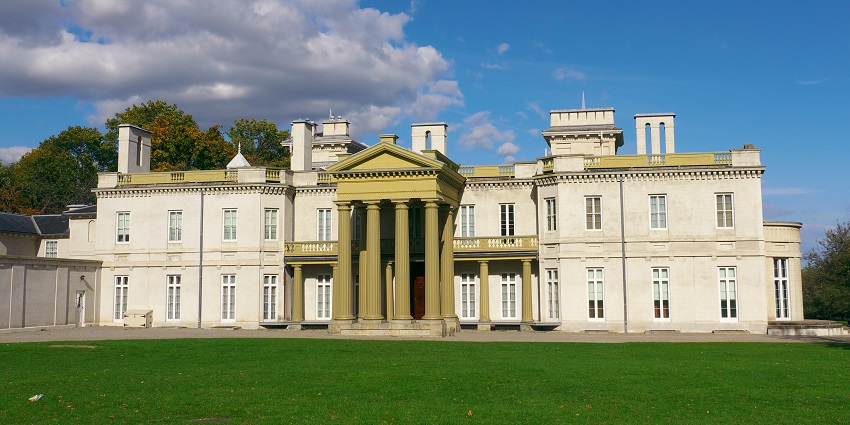 The grand neoclassical façade of Dundurn Castle is surrounded by lush green lawns.