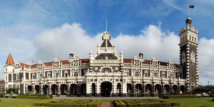 A grand Edwardian Baroque-style railway station with a striking clock tower stands, one of the most iconic architectural monuments in New Zealand.