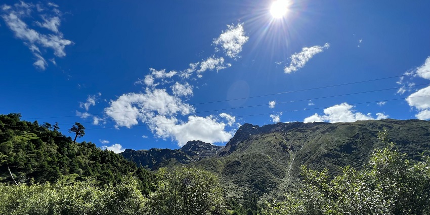 A secluded valley full of thick forest, and a stream running along the mountains under a clear bright sky