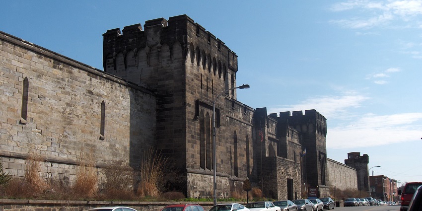 Eastern state penitentiary with tall walls, watch towers and multiple cars, one of the historical places in Philadelphia.