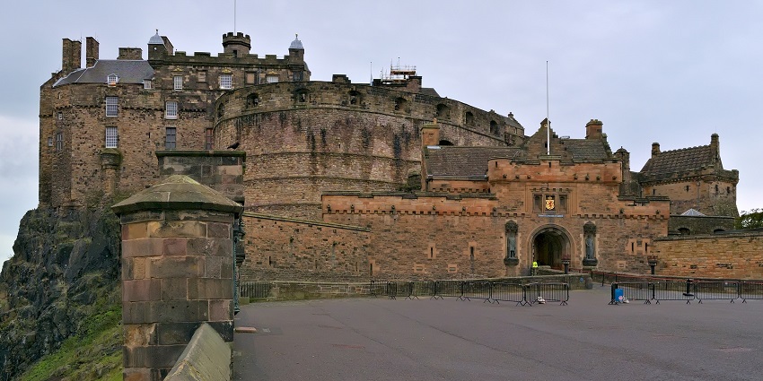 An image of Edinburgh Castle with entrance gate, barricades and traditional British architecture.