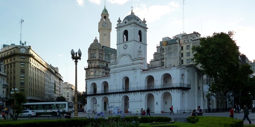 El Cabildo with white architecture, a clock on the top of the building and a big clock tower