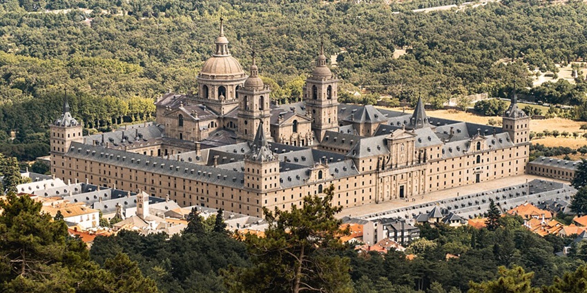 El Escorial with traditional Spanish architecture, grey roofs, and surrounded by greenery