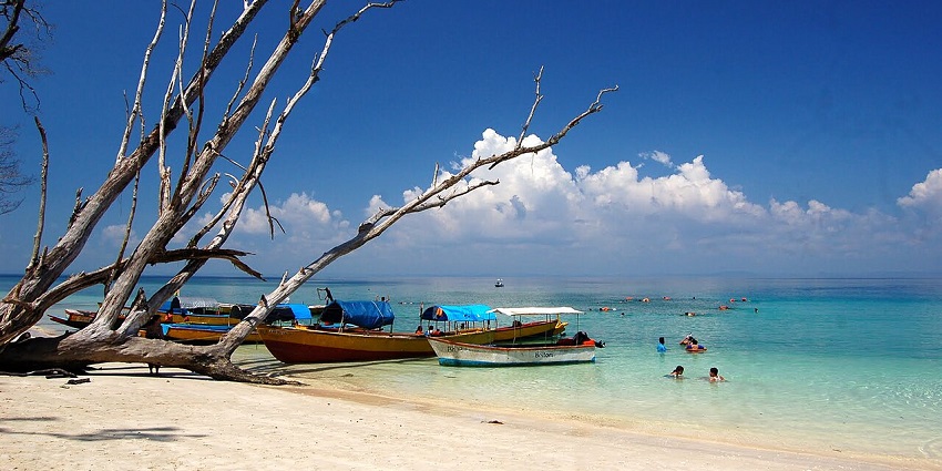 Elephant Beach with boats lined up on the shore with crowds enjoying the clear water.
