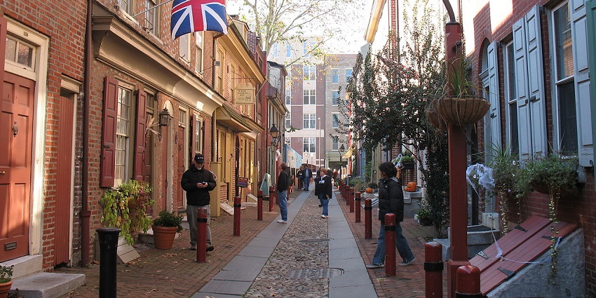 Elfreths’s Alley in Philadelphia with unique street lamps, people on the streets and a flag
