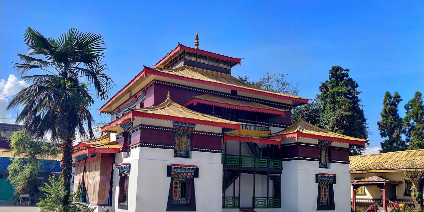 Front view of Enchey Monastery with white walls and golden rooftop glowing under sunlight.