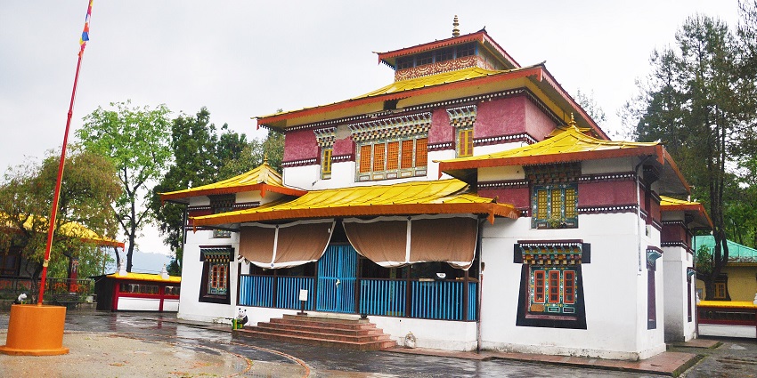 Enchey Monastery with a wet courtyard and vibrant facade surrounded by trees, one of the top places to visit in Gangtok in April.