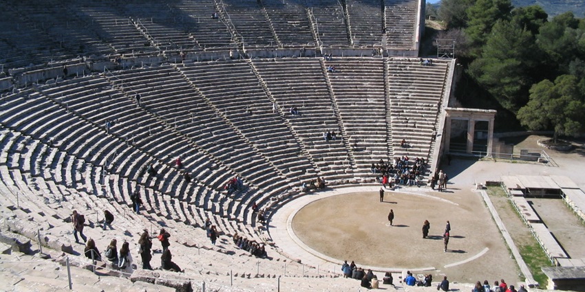 Ancient Greek amphitheater at Epidaurus with stone seating and people exploring the site, one of the top historical places in Greece.