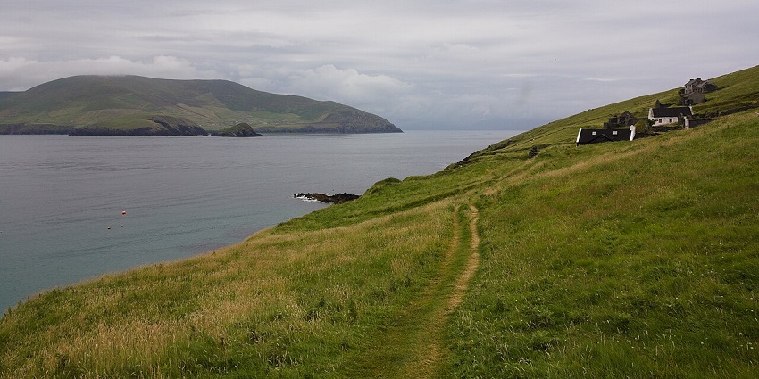 Things to do in Dingle, Ireland, include a tour boat approaching the rugged, green Great Blasket Island.