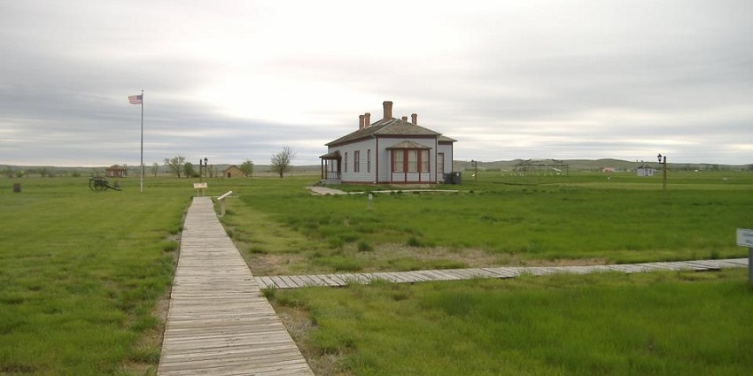 Fort Buford historic site with wooden buildings, grassy grounds, and wide open skies.
