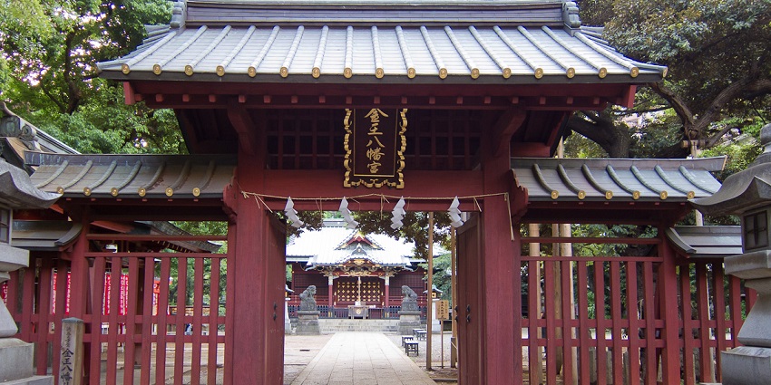 Traditional wooden entrance gate of Konno Hachiman Shrine in Shibuya, surrounded by greenery and stone pathway.