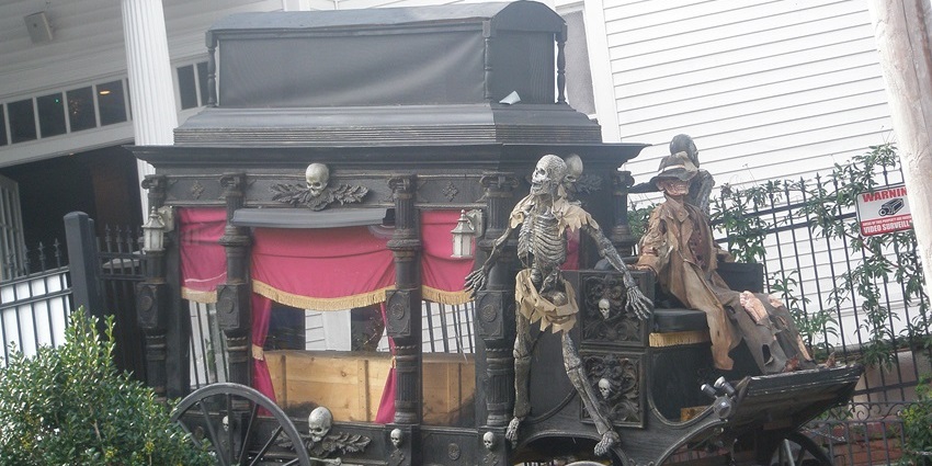 A picture of a cradle outside a horror house decorated with skeletons for a creepy appearance