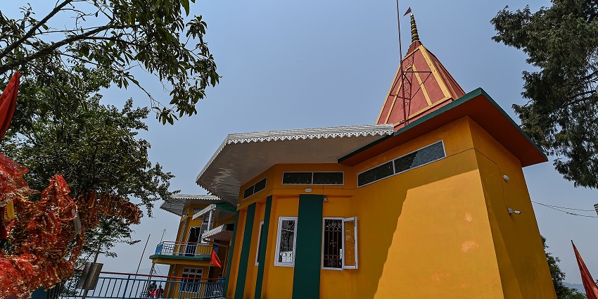 Ganesh Tok temple, Gangtok, with yellow walls, open windows, and prayer flags around it.