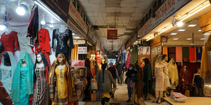 Street view of colorful clothing shops displaying a variety of garments and fabrics.