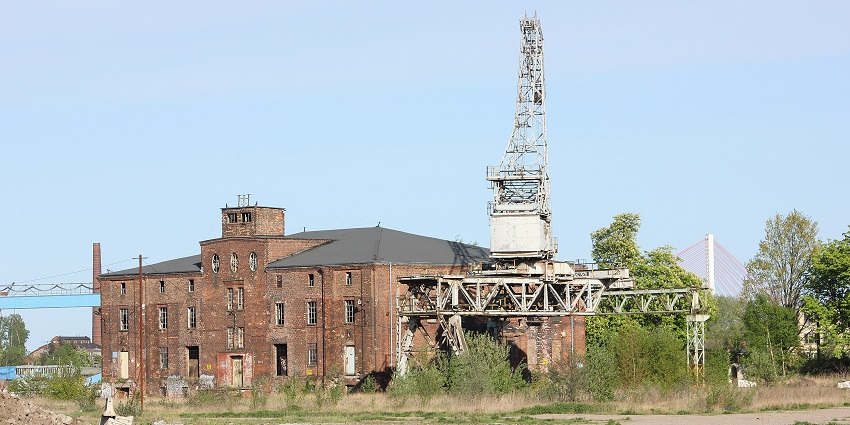 Gdańsk Crane and shipyard with tall abandoned crane & building and green trees