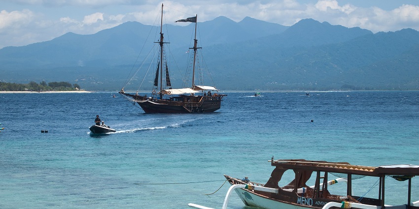 Traditional wooden boats floating on the crystal-clear waters at one of the top beach destinations and scenic places to visit in Indonesia.
