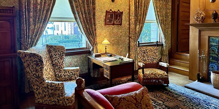 Interior of Glessner house with unique designs on the walls, two sofas, table and lamps.