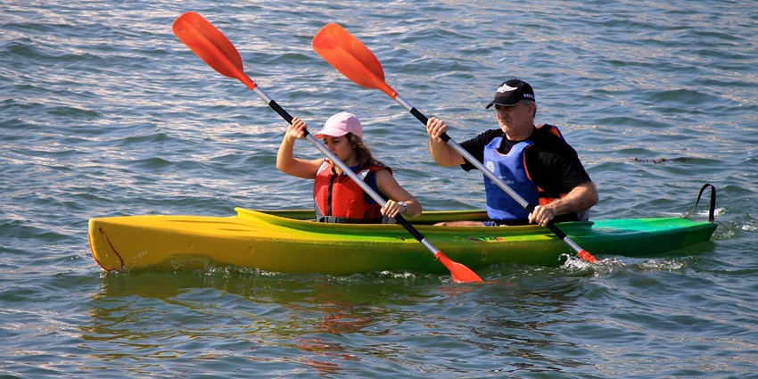 A couple kayaking in the sea, paddling through calm waters with clear skies in Koh Phangan.