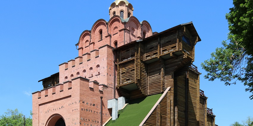 View of the historic Golden Gate of Kyiv with ancient stone walls and a reconstructed wooden roof.