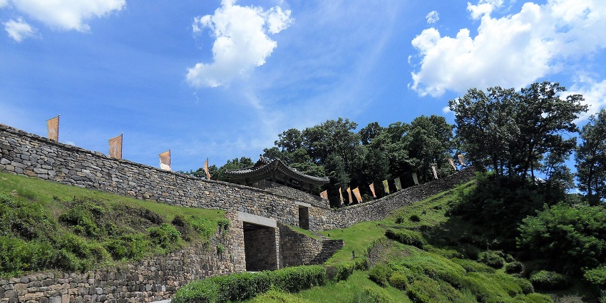 Gongsanseong Fortress with a wall made up of stone, a small entrance and multiple flags