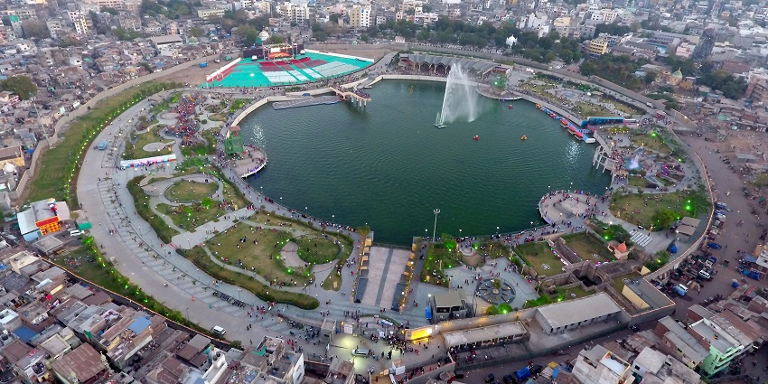 A stunning aerial view of a beautifully lit urban lake surrounded by a bustling cityscape.