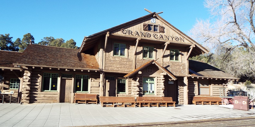Wooden Grand Canyon train station with benches and railway tracks in the foreground.