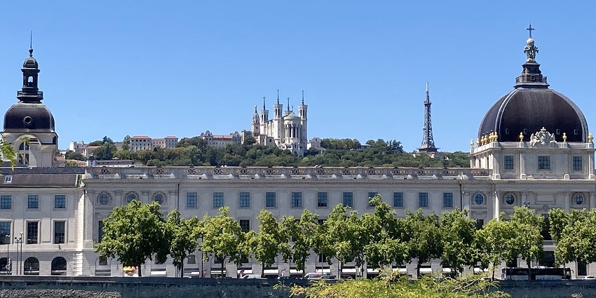 Grand Hôtel-Dieu with black domes, crosses on the top, multiple windows and green trees