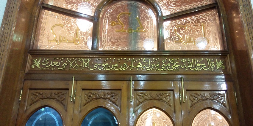 Grand Mosque of Kufa with gold architect, Islamic sculptures on the wall and people standing