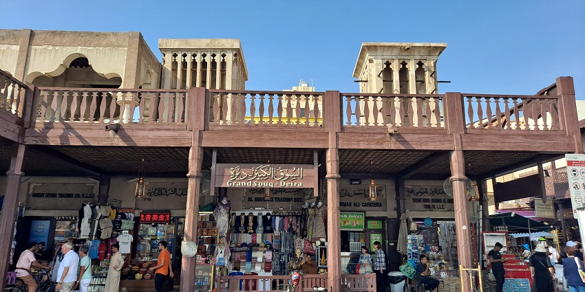 Front view of Grand Souk Deira with shops, wind towers, and people walking and shopping.