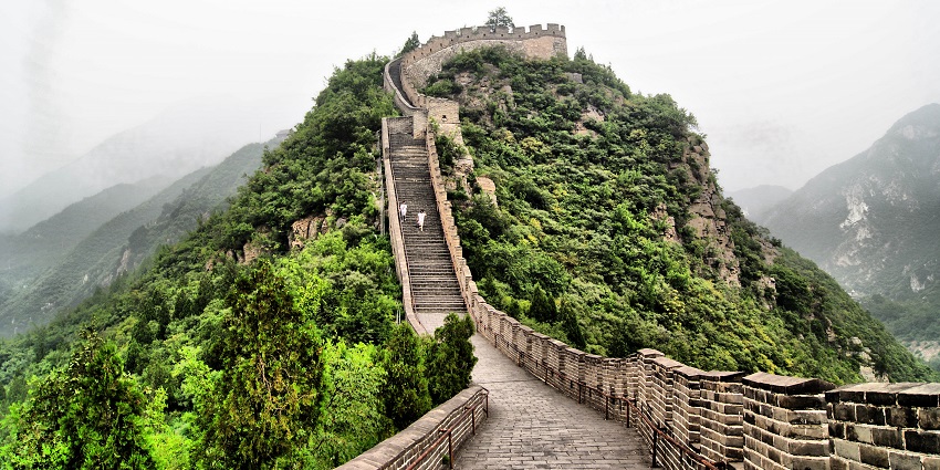 The Great Wall of Badaling with a wall made up of stones, stairs and people climbing up