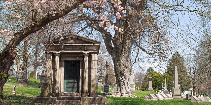 Green-wood cemetery with a mausoleum, tombstones in the back and cherry blossom tree