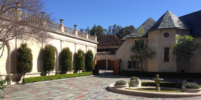 Greystone mansion with greystone architecture, multiple windows, grey walls, and green grass