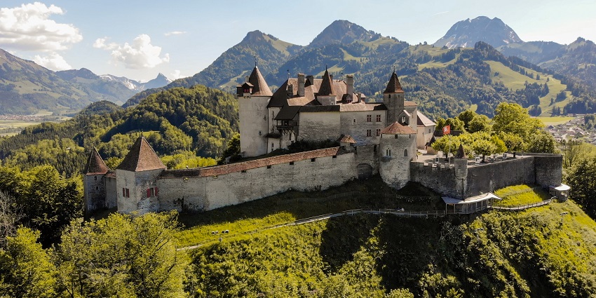 Château de Gruyères, a majestic medieval castle in Switzerland, surrounded by green hills and trees.