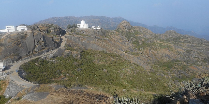 Guru Shikhar with distant white buildings and mountains, one of the places to visit in Mount Abu in April