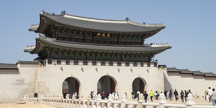 Gwanghwamun Gate with black-themed architecture, people entering and signage on top
