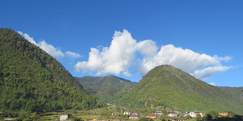 Haa valley in Bhutan with distant traditional houses and buildings surrounded by green hills.