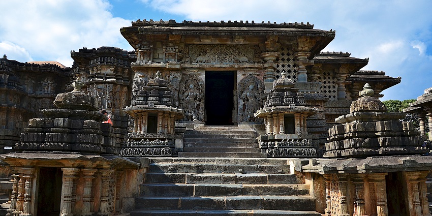 Temple stone panels are beautifully carved with rich details of mythology beneath blue skies.