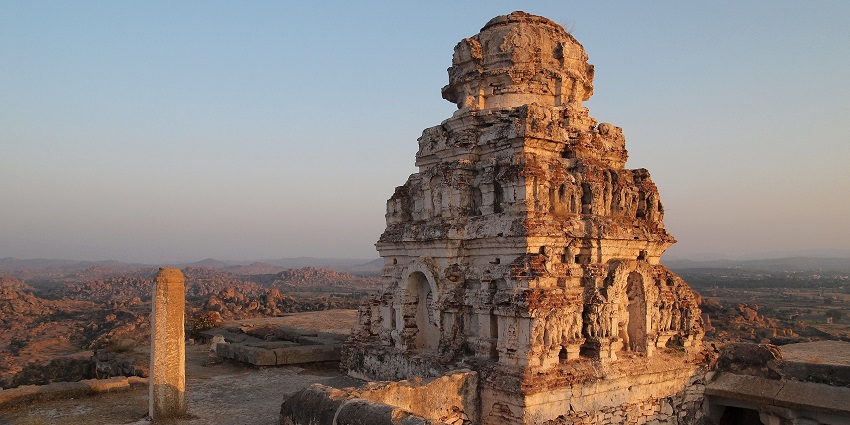 An ancient hilltop temple surrounded by rocky terrain and panoramic views under a clear sky.