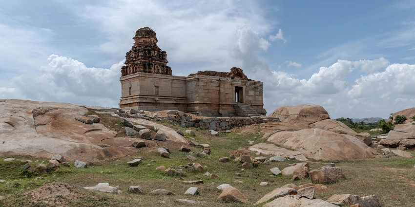 Ancient stone temples and boulders at Hampi under clear skies, capturing rich historical scenery.