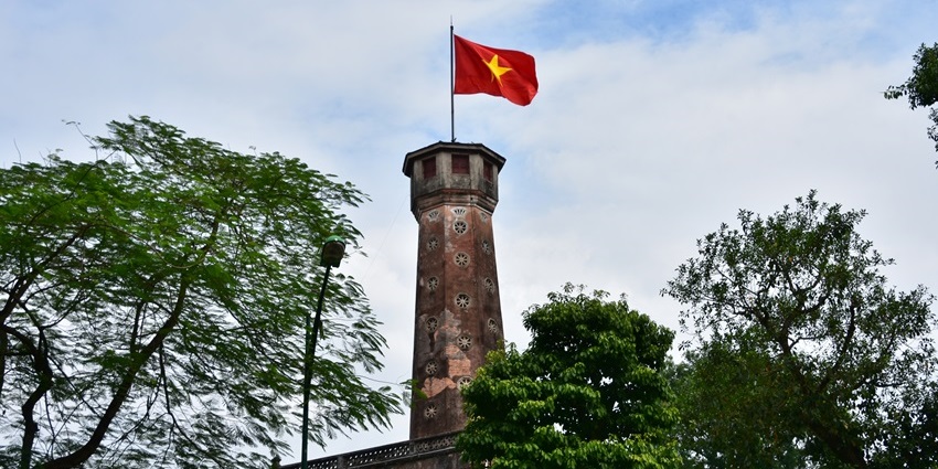 Stone structure of Hanoi Flag Tower with red Vietnamese flag.