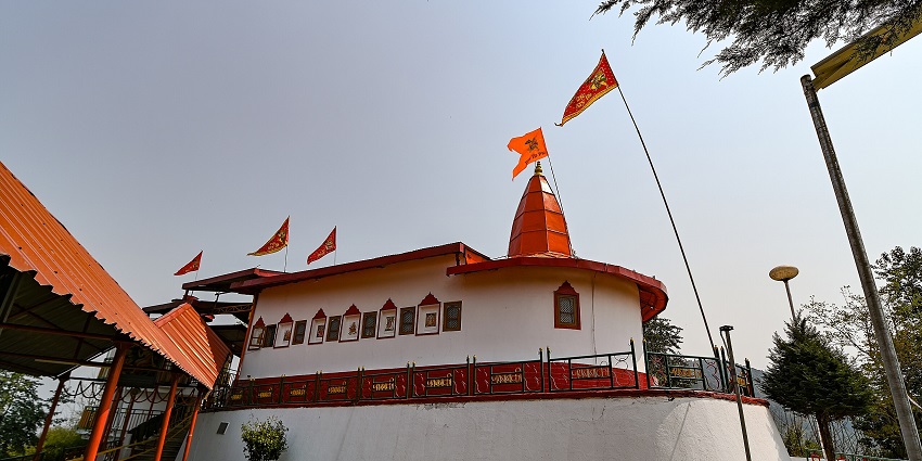 Wide view of the Hanuman Tok temple complex with red roofs and orange flags fluttering.
