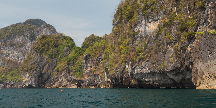 Hat Chao Mai National Park with a blue water body, big rocky cliffs and greenery on the rocks.