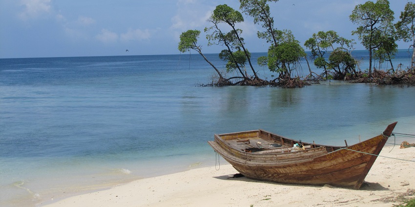 A boat in the sand on a tranquil beach at Havelock Island, one of the places to visit in Andaman in April.